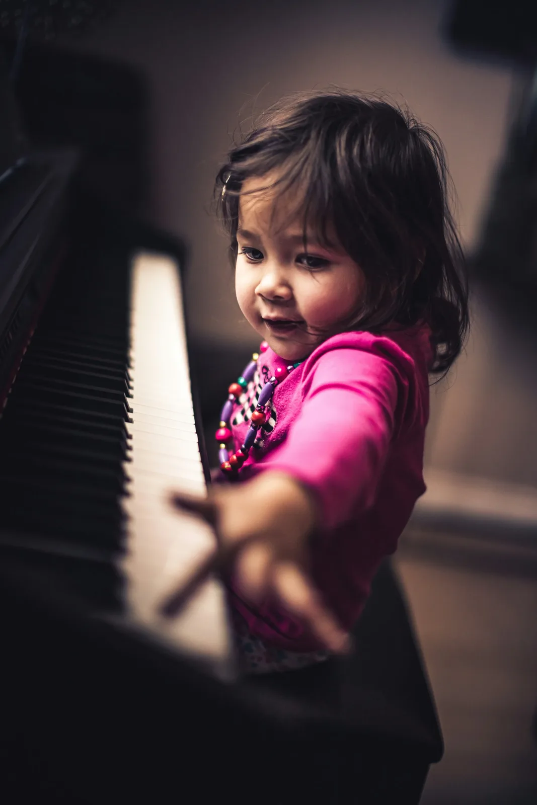 Tout-petit tendant la main vers les touches du piano