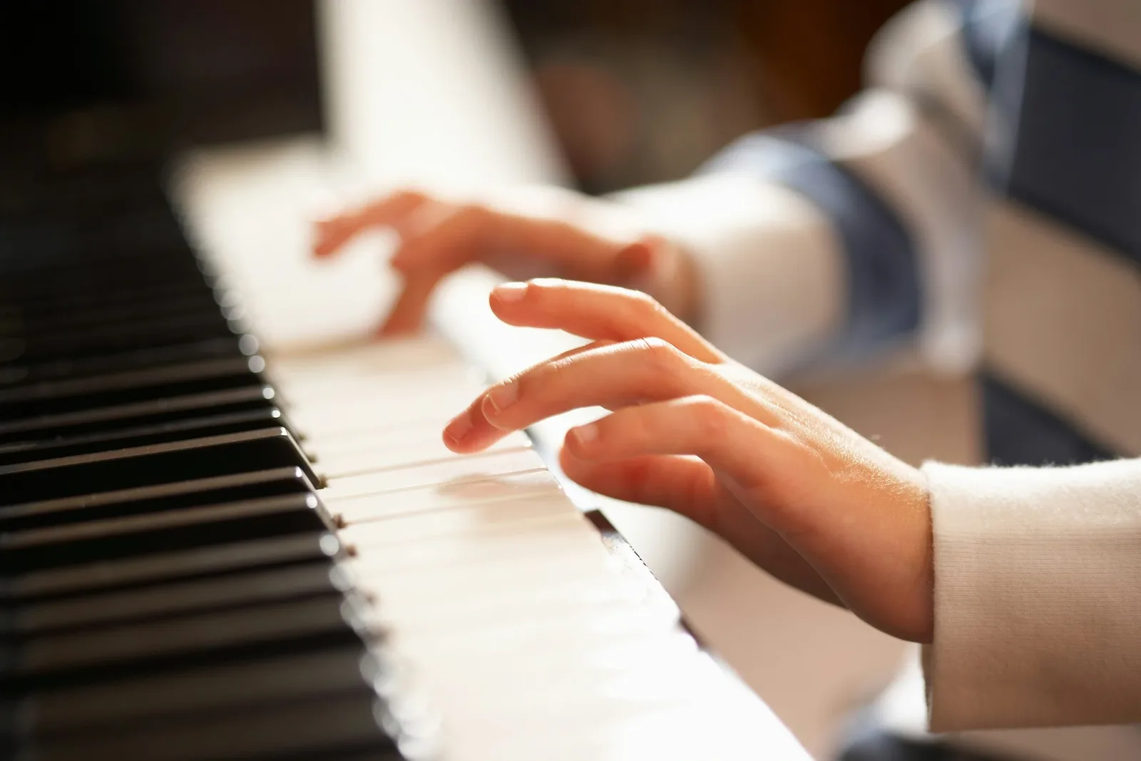 Close-up of a child's hands playing the piano